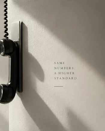 Vintage corded telephone handset mounted on a sunlit wall, with the tagline "Same numbers. A higher standard."